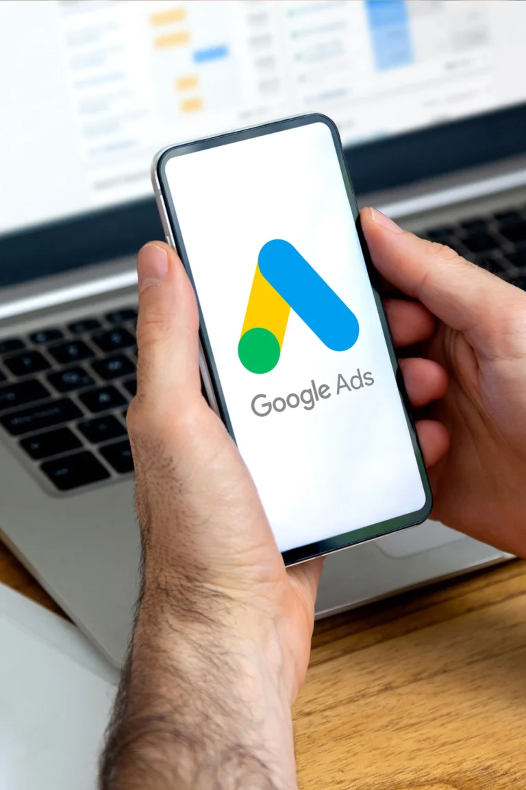 A marketer holds up a mobile device with Google Ads on it